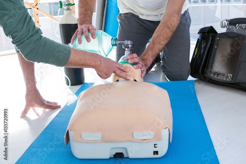 Paramedics practicing cardiopulmonary resuscitation on mannequin