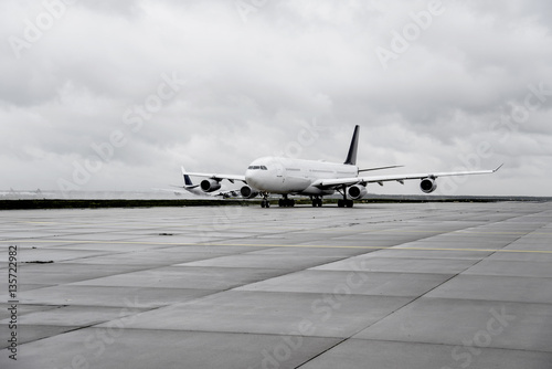 airplane on taxiway with another jet taking off on runway in background
