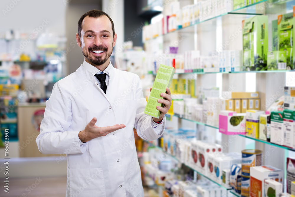 Smiling man pharmacist showing right drug