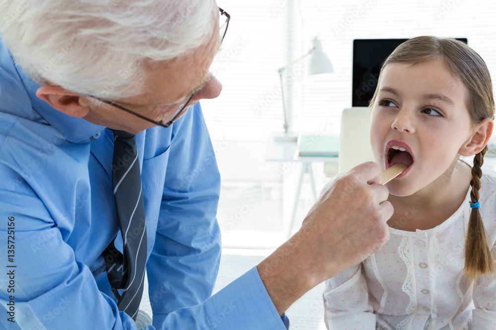 Doctor examining patient throat by using tongue depressor Doctor examining patient throat by using tongue depressor