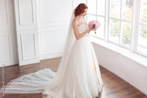 Bride in white wedding dress and long veil with bouquet of flowers