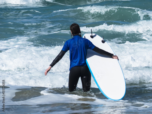 Surfer with surf board trying to get out trough the surf to catc photo