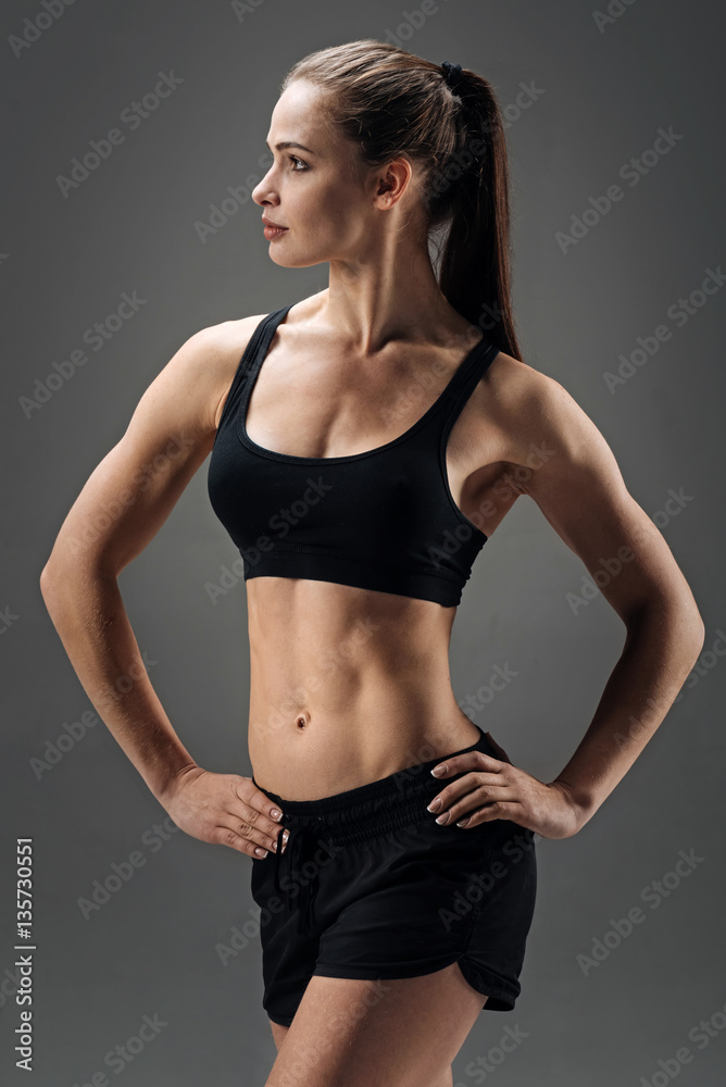 Strong girl demonstrating her muscles on a grey background Strong girl demonstrating her muscles on a grey background