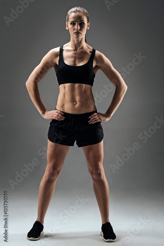 Athletic girl demonstrating her muscles on a grey background