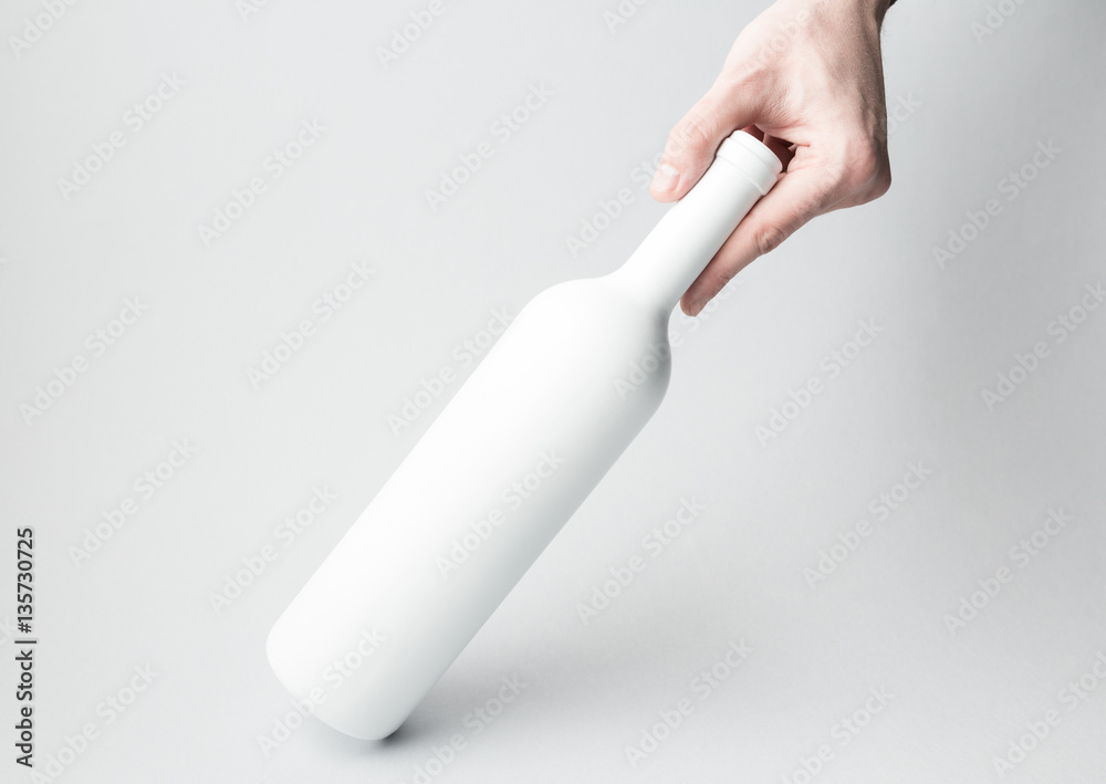 Hand is holding wine bottle on gray background Hand is holding wine bottle on gray background