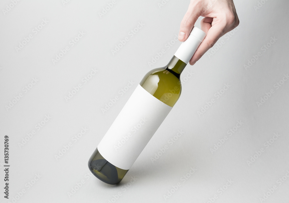 Hand is holding wine bottle on gray background Hand is holding wine bottle on gray background