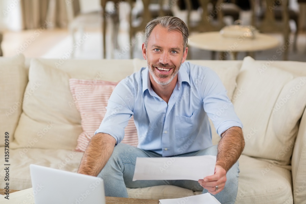 Happy man holding a bill in living room