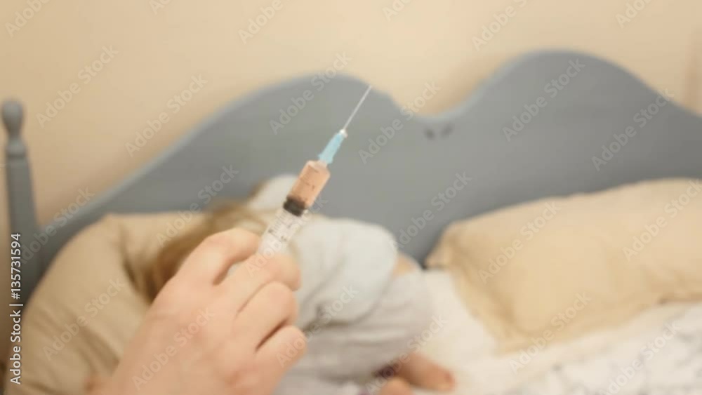 A little girl in her bed looking at a syringe. She's really scared.
