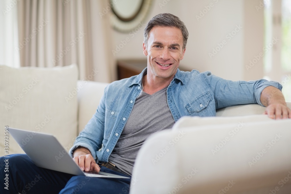 Portrait of smiling man sitting on sofa with laptop Portrait of smiling man sitting on sofa with laptop
