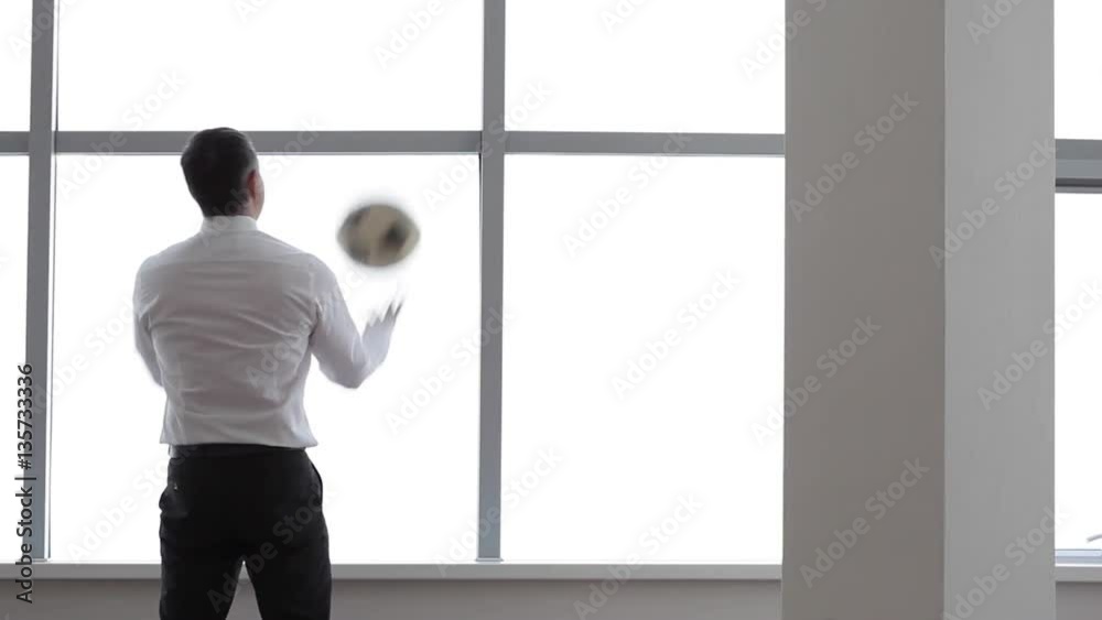 Football Team Manager/Businessman holds a football and spins it on his finger