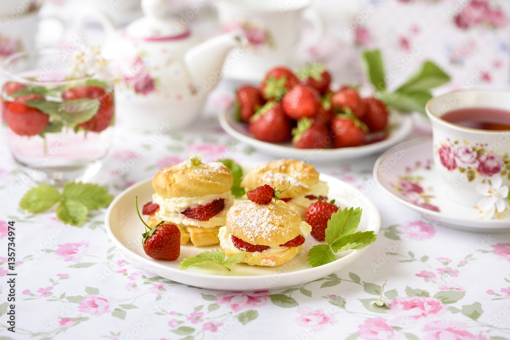 Profiterole or cream puff cakes or filled with whipped cream,g served with strawberries Profiterole or cream puff cakes or filled with whipped cream,g served with strawberries