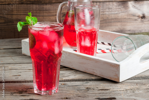 Summer iced drink - tea or juice with ice and mint. On rustic wooden table, with white tray, copy space