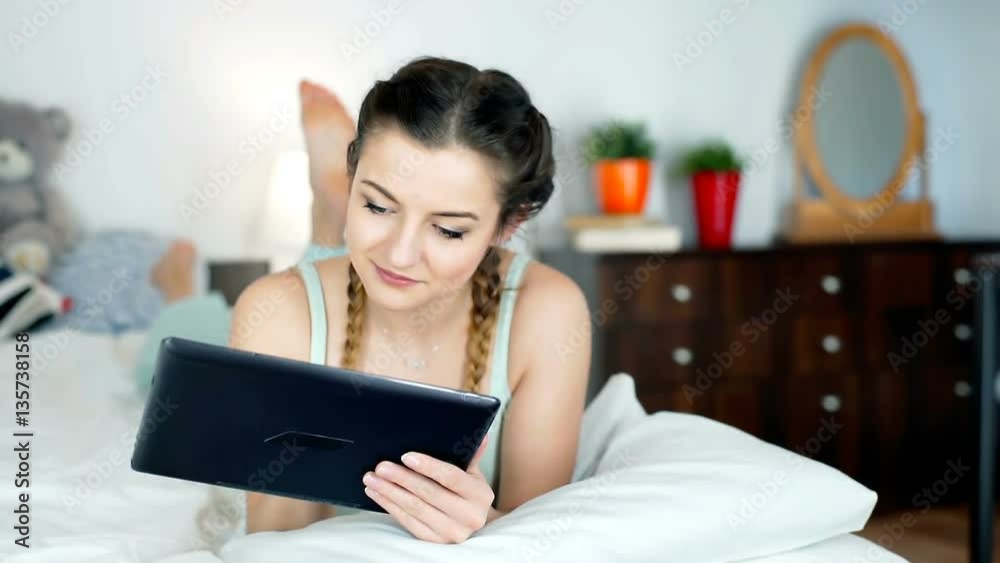 Teenager lying on the bed and browsing internet on tablet, steadycam shot
Teenager lying on the bed and browsing internet on tablet, steadycam shot