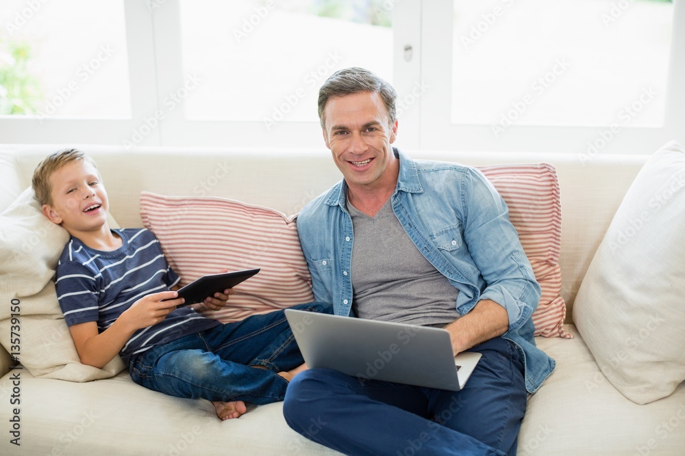 Father and son using laptop and digital tablet in living room Father and son using laptop and digital tablet in living room