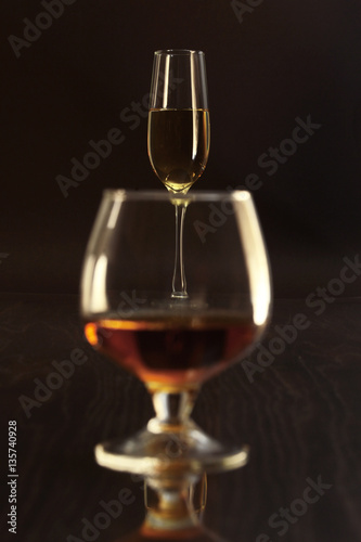 Glasses with white wine and cognac or whisky on mirror table. Celebrities composition.