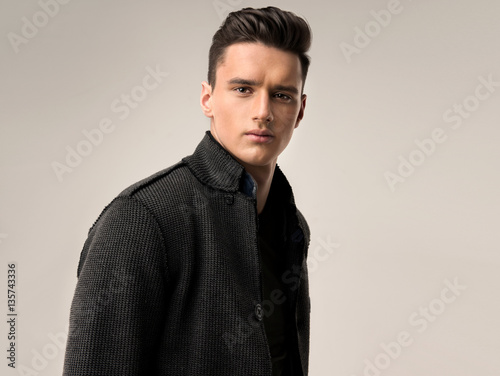 Fashion portrait of a handsome man with trendy hairstyle in a stylish jacket .