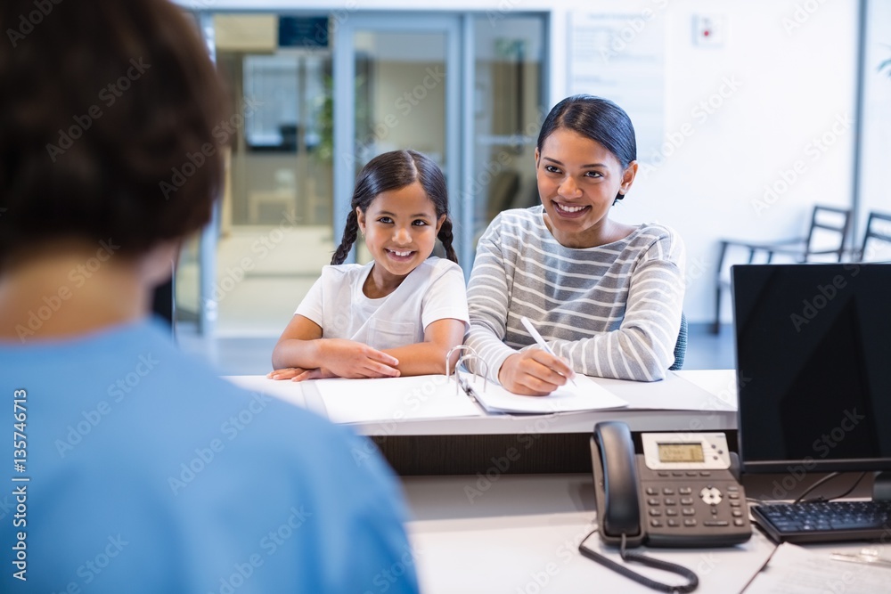 Mother and daughter filling out paperwork at counter Mother and daughter filling out paperwork at counter