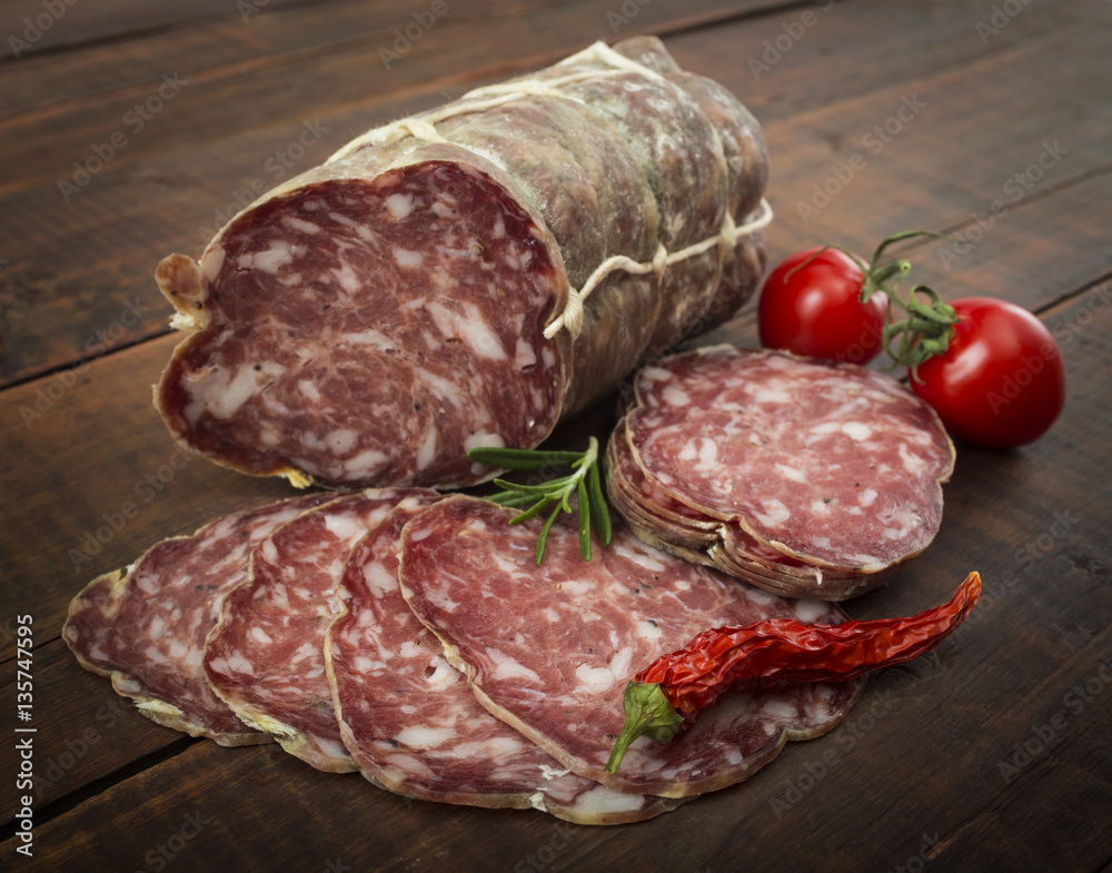 Italian salami with red pepper cherry tomatoes on a wooden background Italian salami with red pepper cherry tomatoes on a wooden background