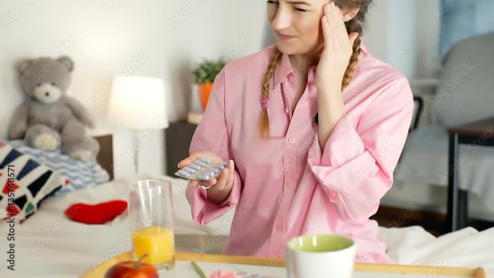 Girl holding pills and having painful headache in the morning, steadycam shot
