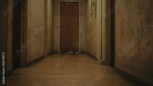 Walking inside a long dark hallway of old apartment building.