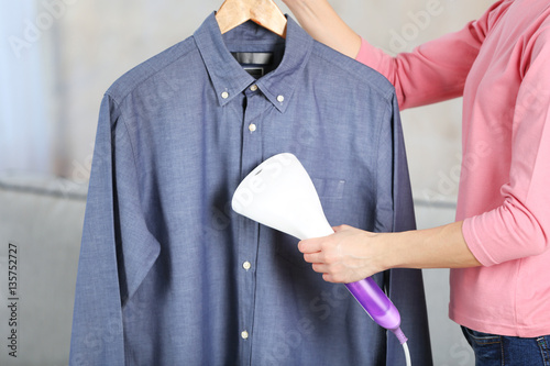 Woman ironing shirt with garment steamer