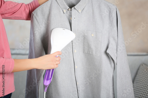 Woman ironing shirt with garment steamer