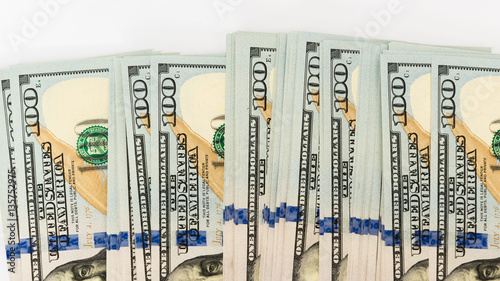 Heap of hundred dollar banknotes on white surface