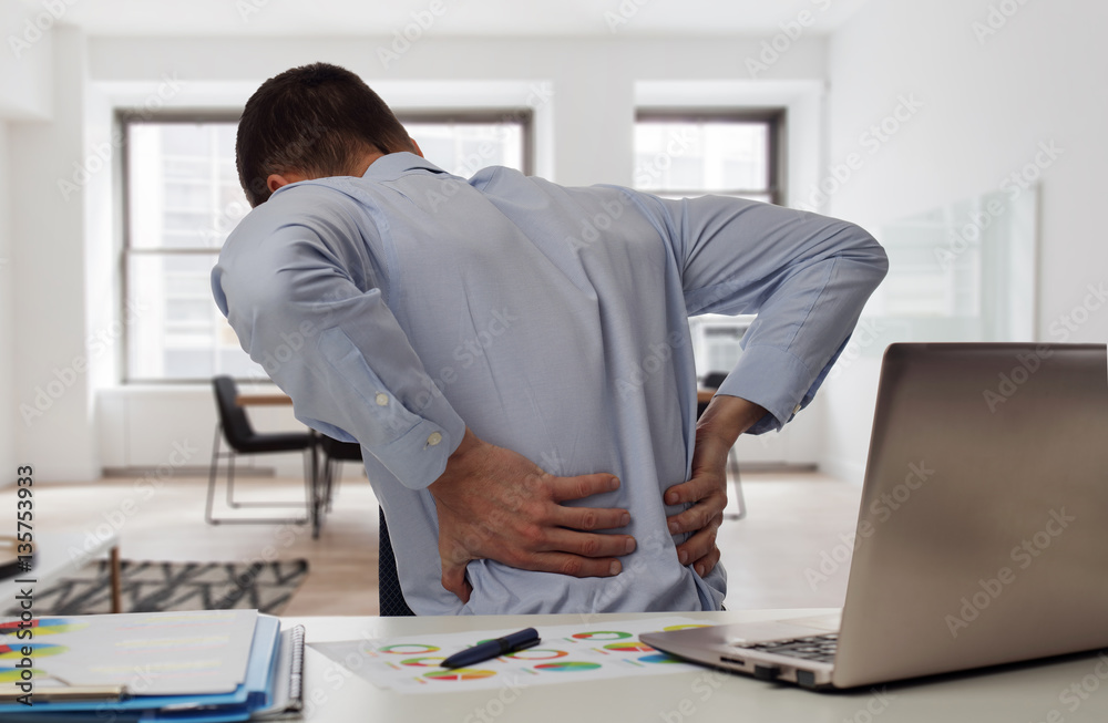Business man with back pain in an office . Pain relief concept