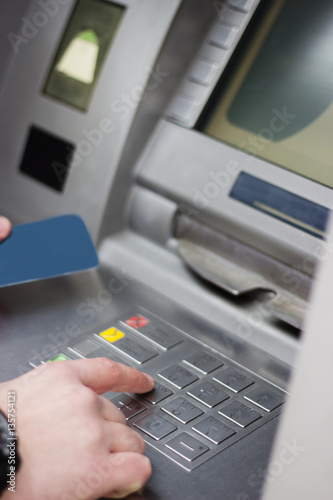 Hand of a man with a credit card, using an ATM. Man using an atm machine with his credit card. © Addoro