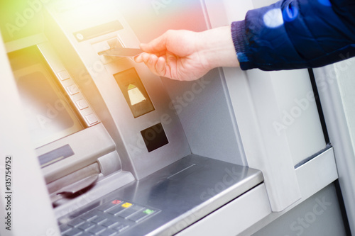 Hand of a man with a credit card, using an ATM. Man using an atm machine with his credit card. photo