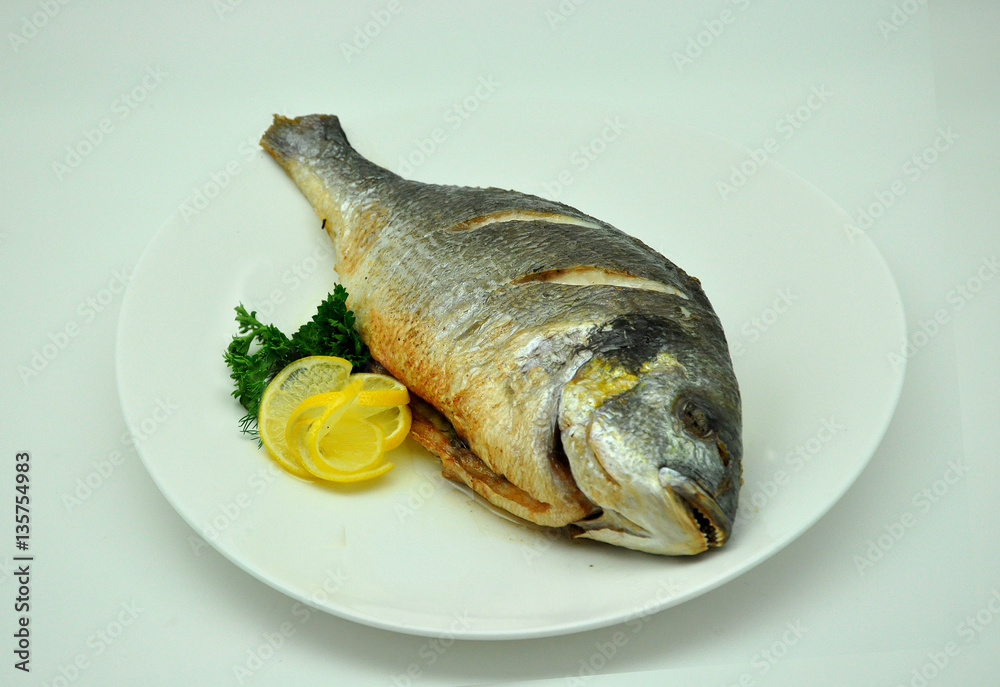 fried carp fish with lemon and parsley on a white background fried carp fish with lemon and parsley on a white background