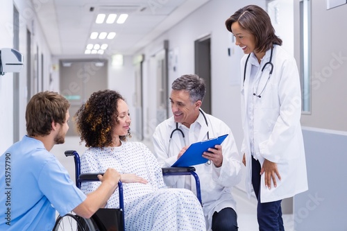 Doctors interacting with pregnant woman in corridor