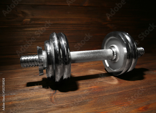 Metal collapsible dumbbell on wooden background