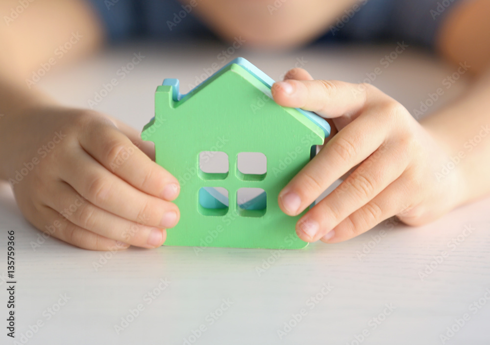 Child holding figures in shape of houses, closeup. Adoption concept Child holding figures in shape of houses, closeup. Adoption concept