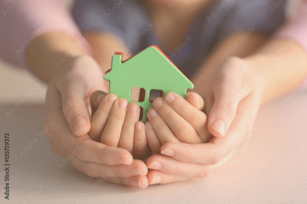 Child and adult person holding figure in shape of house, closeup. Adoption concept Child and adult person holding figure in shape of house, closeup. Adoption concept