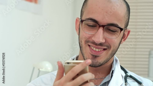 Medical worker checking his phone and laughing photo