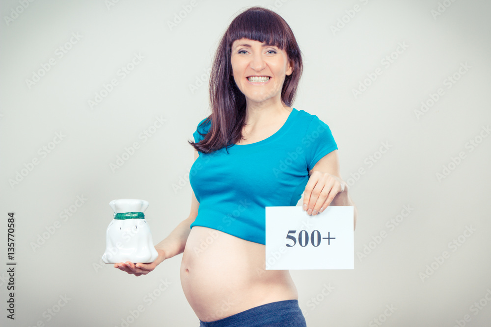 Pregnant woman holding piggy bank and inscription 500+, social program and policy in Poland Pregnant woman holding piggy bank and inscription 500+, social program and policy in Poland