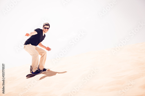Fototapeta Naklejka Na Ścianę i Meble -  Tourist Sandboarding In The Desert