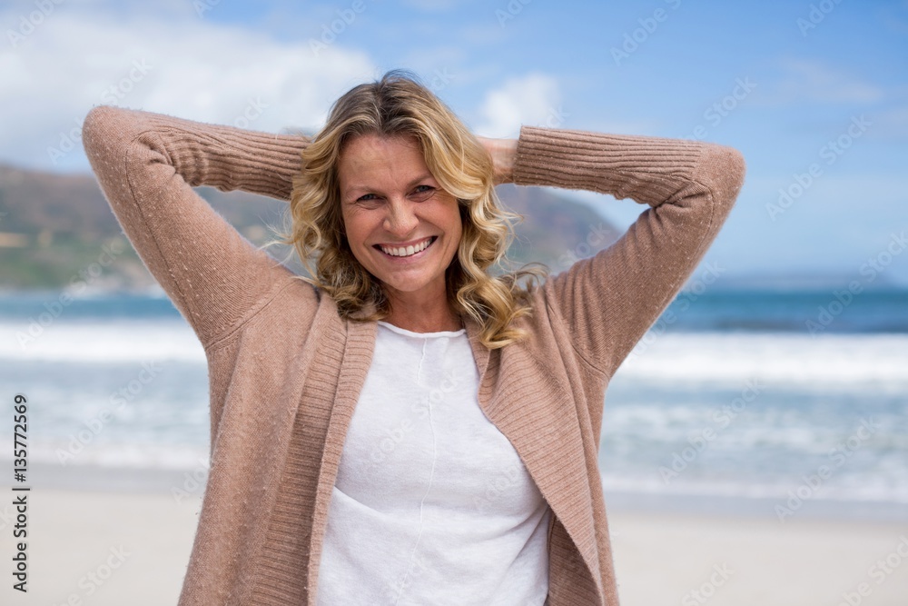 Mature woman with hands behind head standing on the beach Mature woman with hands behind head standing on the beach
