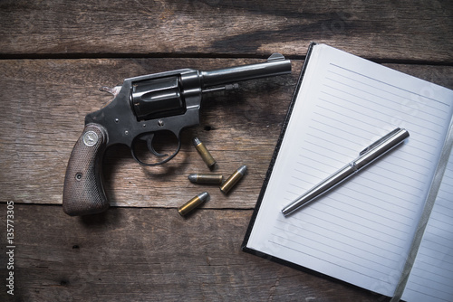 Gun and ammunition and blank notebook on wooden table. top view photo