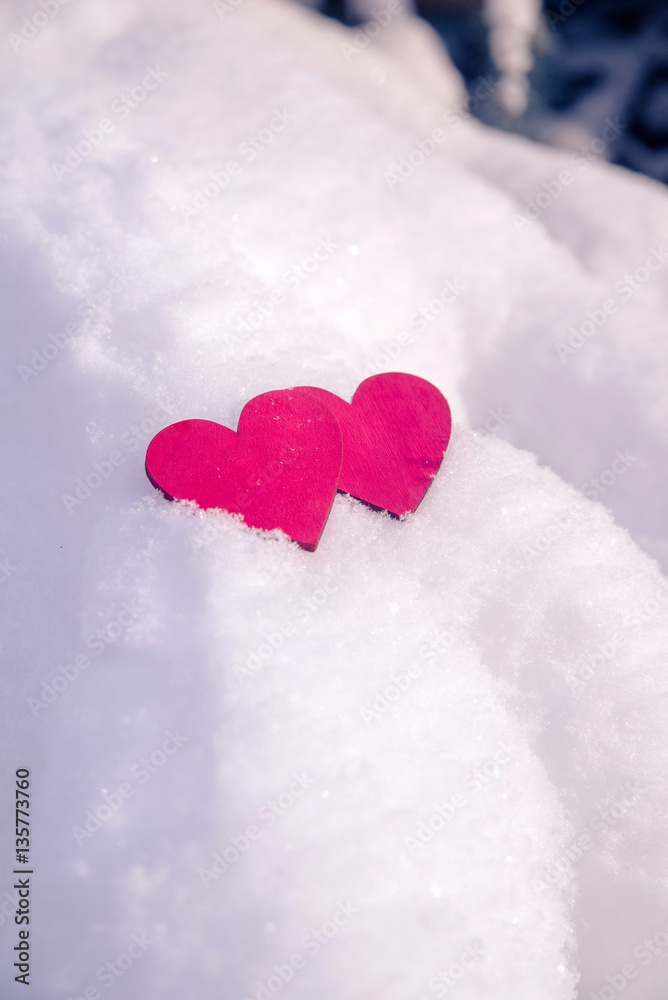 Fototapeta premium Two red hearts lie on the snow 