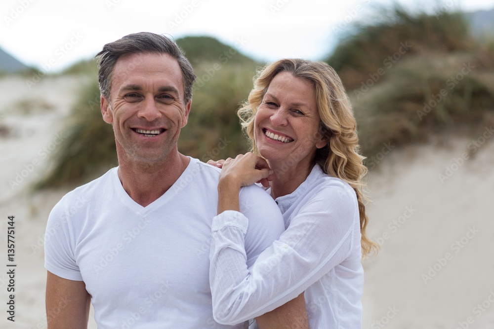 Obraz premium Smiling mature couple standing together on the beach