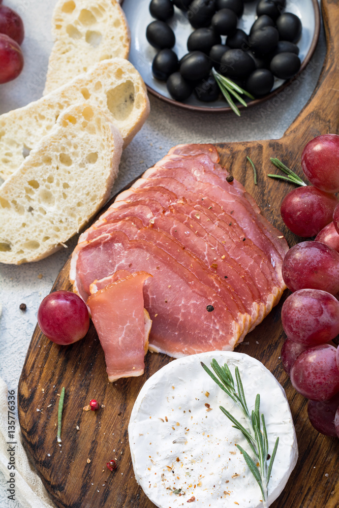 Italian appetizer plate: cured meat, cheese, grapes, olives and fresh bread. Top view