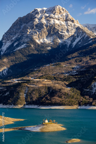 Serre Poncon Lake and Saint Michel Chapel in the Southern French Alps. The peak of Grand Morgon rises above Saint Michel Bay. Hautes Alpes, France