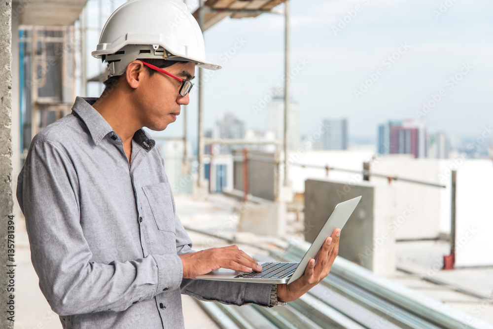 Engineers working on a building site holding a laptop.