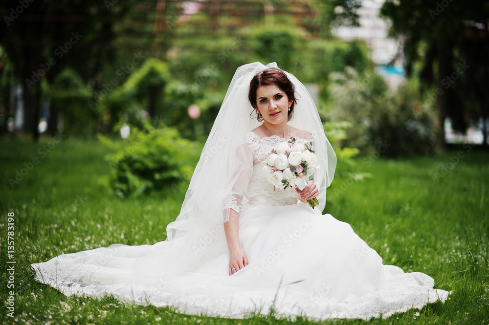 Portrait of amazing brunette bride with wedding bouquet in hands
