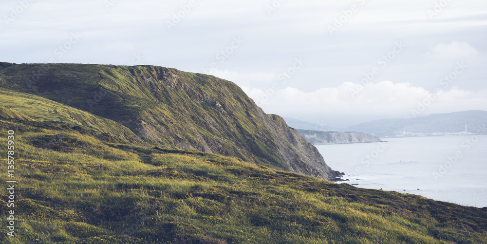 Sunset in the mountain natural landscape. Green valley on background dramatic sky, clouds, sea ocean. Panorama horizon perspective view of scenery hills Northern Spain alps. Travel mockup concept