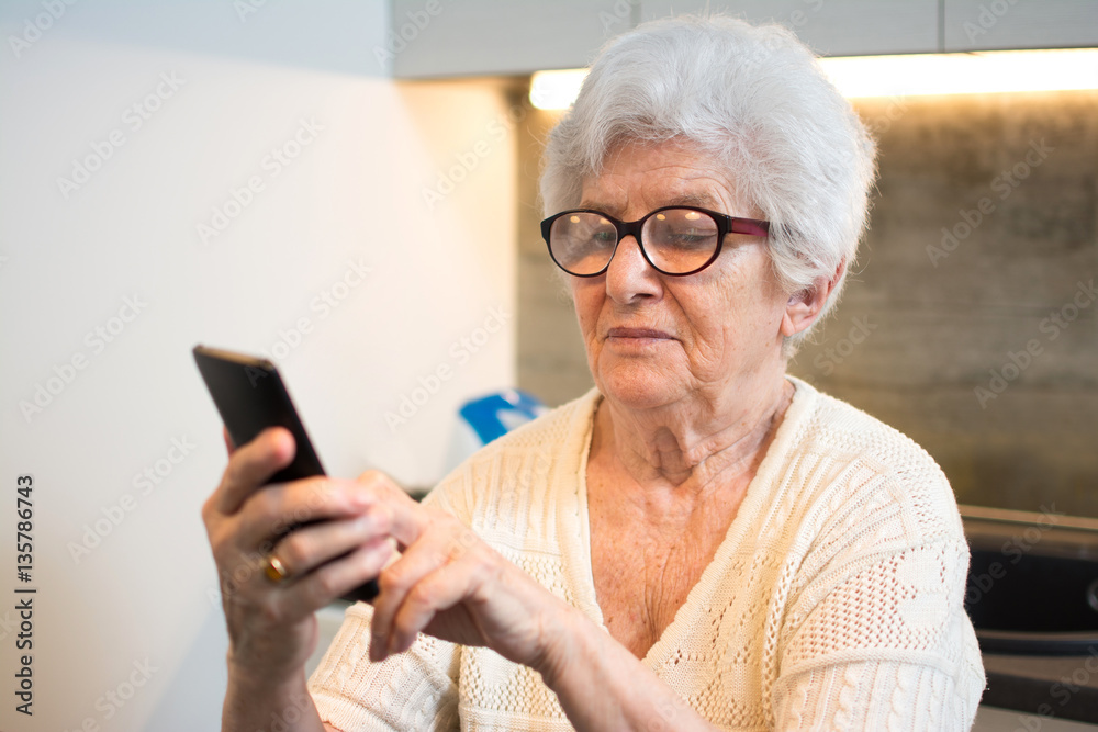 Happy senior woman using smartphone at home. Happy senior woman using smartphone at home.