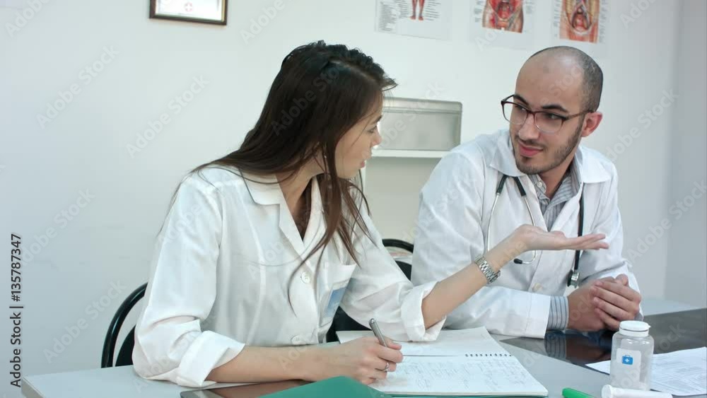 Young couple of doctor and nurse laughing at each other after a quarrel Young couple of doctor and nurse laughing at each other after a quarrel