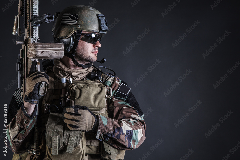 United states Marine Corps special operations command Marsoc raider with weapon. Studio shot of Marine Special Operator half-turning black background